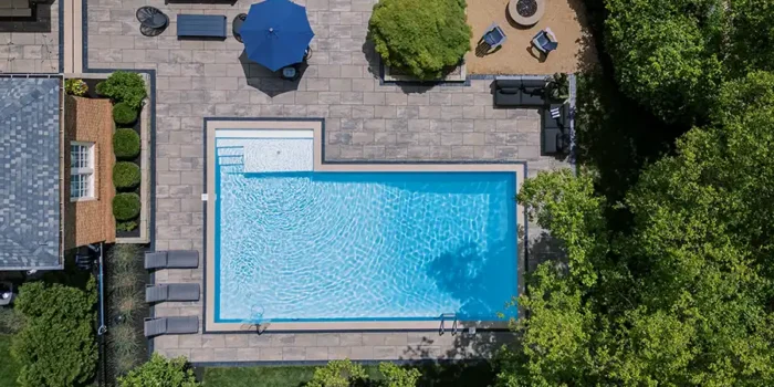 Aerial view of a custom Unilock Beacon Hill XL Smooth paver pool deck with Copthorne Basalt accents, pool coping, outdoor seating and a separate fire pit area in New Albany, Ohio.