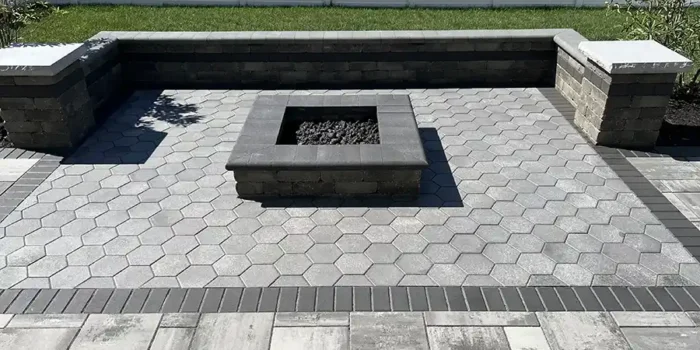 Custom Unilock Beacon Hill Smooth Granite Fusion paver patio in New Albany Ohio with hex paver inlay, limestone seating walls, and gas fire pit.