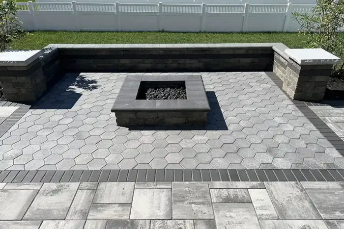 Custom Unilock Beacon Hill Smooth Granite Fusion paver patio in New Albany Ohio with hex paver inlay, limestone seating walls, and gas fire pit.